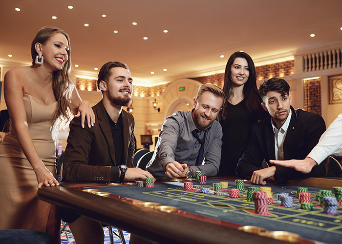 Group of friends enjoys winning poker roulette in a casino.